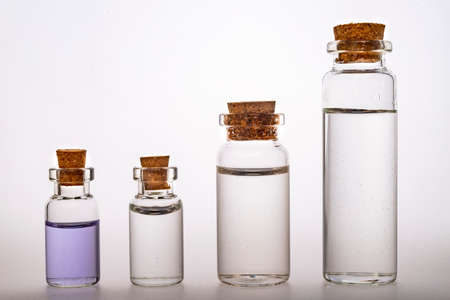 Glass bottles with liquid closed with a stopper. Container for storing liquids. Light background.の写真素材