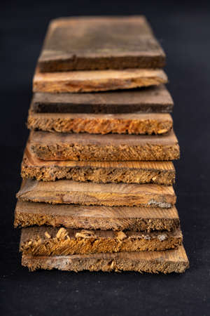 Raw boards piled up. Wood on the table in the workshop. Dark background.