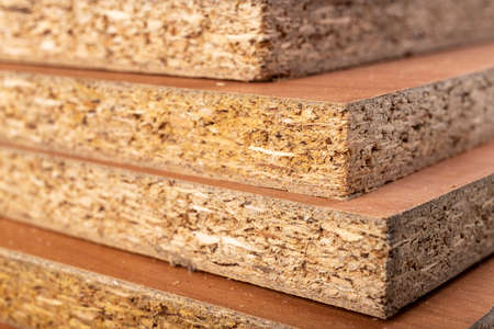 Particle board for the construction of home furniture. Material stacked in the carpentry shop. Light background.の写真素材