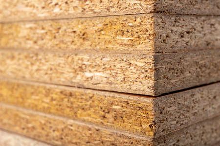 Particle board for the construction of home furniture. Material stacked in the carpentry shop. Light background.の写真素材