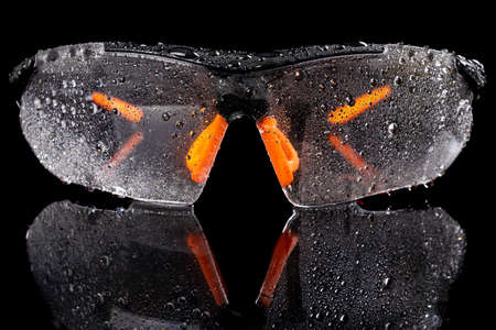 Wet glasses for eye protection at work. Health and safety accessories for production workers. Dark background.の写真素材