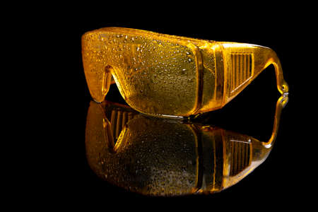 Wet glasses for eye protection at work. Health and safety accessories for production workers. Dark background.の写真素材