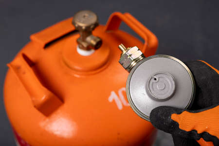 Propane-butane gas cylinder and reducer. Combustible gas used in households. Dark background.の写真素材