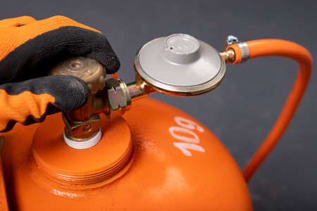 Unscrewing the propane-butane gas cylinder. Combustible gas used in households. Dark background.の写真素材