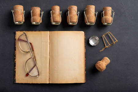 Old yellowed notebook and champagne corks. A place to save your memories of New Year's Eve. Dark background.の写真素材