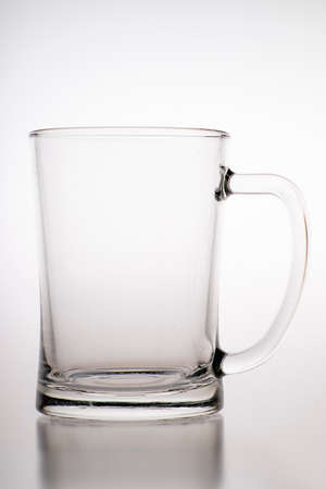 Pouring water into a mug. Glass container for weak carbonated alcohol. Light background.の写真素材