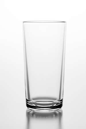 Empty glass on a white table. Glass container for storing water. Light background.の写真素材