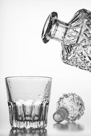 Decorated carafe and a small water glass. Decorative containers for serving water and alcohol. Light background.の写真素材