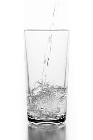 Pouring sparkling water into a glass. A container for storing liquids. Light background.の写真素材
