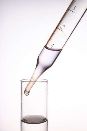 Glass pipette and measuring cup with liquid. Accessories in the chemical laboratory. Light background.の写真素材