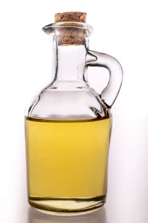 Oil in a glass container with a stopper. A jug of olive oil used in the household. Light background.の写真素材
