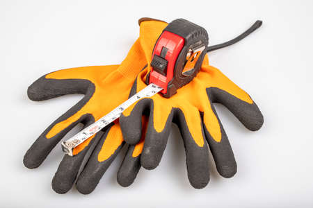 Metal measuring tape with protective gloves. Accessories for carpenters to measure. Light...