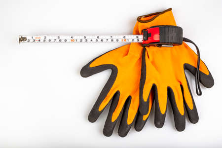 Metal measuring tape with protective gloves. Accessories for carpenters to measure. Light background.の写真素材