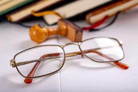 Glasses and books with tabs made of string. Old publications and a wooden stamp. Light background.