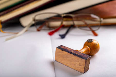 Glasses and books with tabs made of string. Old publications and a wooden stamp. Light background.の写真素材