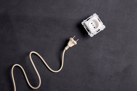 Plug and socket for powering various household appliances. Electrical installation in the house. Dark background.の写真素材