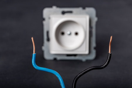 Copper wires and electrical outlet. Minor electrical work in the household. Dark background.