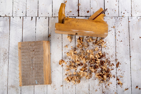 Planing wood with hand tools. Minor carpentry work performed in the workshop. Light background.の写真素材