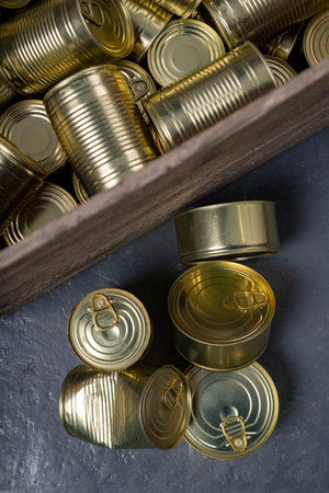 Metal cans of food in a wooden crate. Food stockpiled for hard times. Dark background.の写真素材