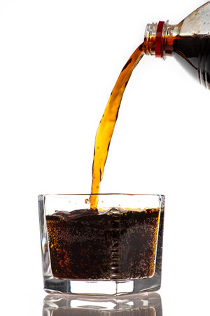 Pouring a sweet drink into a glass. Container for serving drinks. Light background.の写真素材