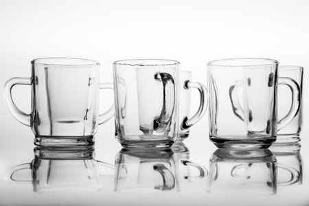 Thick glass mugs stacked. Drinking water storage containers. Light background.の写真素材