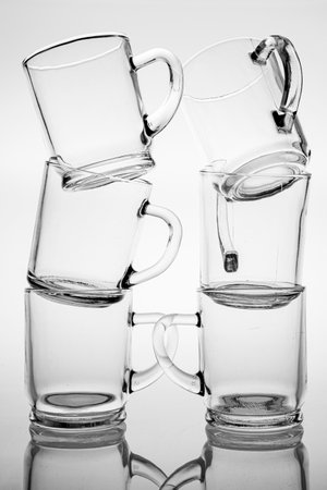 Thick glass mugs stacked. Drinking water storage containers. Light background.の写真素材