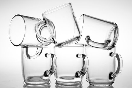 Thick glass mugs stacked. Drinking water storage containers. Light background.の写真素材