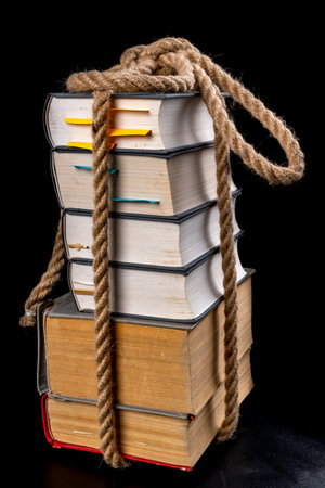 Thick books tied with a strong rope. A thick line around the paper. Dark background.の写真素材