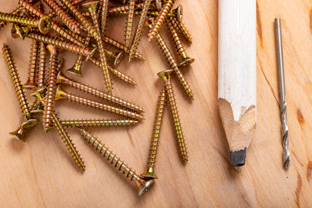 Metal wood screws and a carpenter's pencil. Minor carpentry work in the workshop. Light background.の写真素材