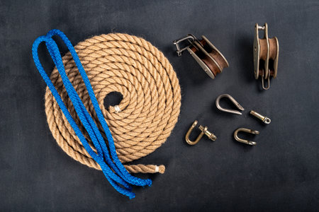 Thick jute rope, two pulleys and a shackle. Sailing accessories used on yachts. Dark background.の素材 [FY310161028221]