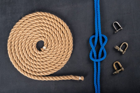 Thick jute rope coiled in the shape of a circle, shackles and a simple knot. Sailing accessories...