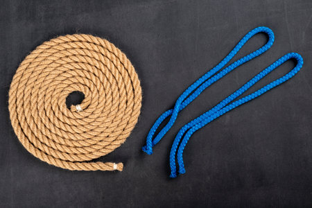 Thick jute rope coiled into a circle and short lines for tying the sails. Sailing accessories used on yachts. Dark background.の写真素材