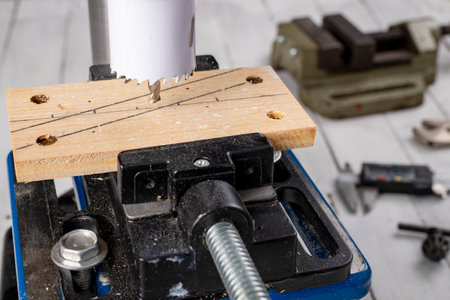 Drilling a large hole in wood. Hole saw used in a table drill. Dark background.の写真素材
