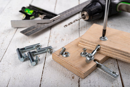 Assembly of the hinge used in the construction of furniture. Minor carpentry work performed in the workshop. Light background.の写真素材