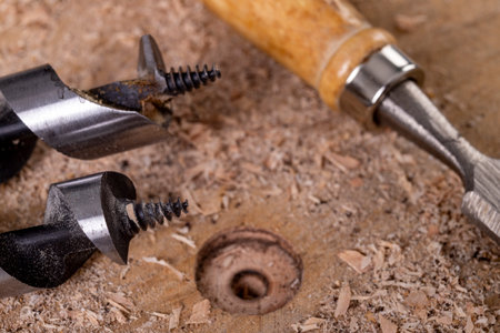 Drilling a hole in raw wood with a drill. Carpentry accessories in the workshop. Light background.の写真素材