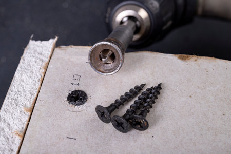 Black screws for fixing plasterboards. Building a wall of drywall. Workplace - construction site.の写真素材