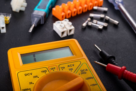 A meter for electrical measurements on a workbench. Accessories for repair and installation of electrical equipment. Dark background.の写真素材