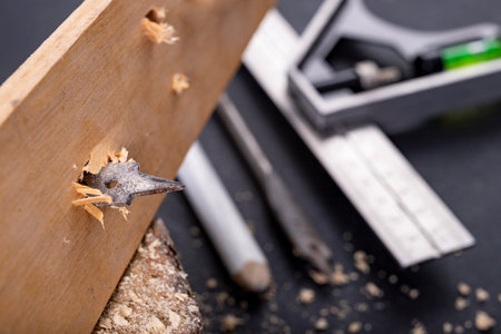 Drilling with a metal drill in a piece of wood. Minor carpentry work in the workshop. Dark...