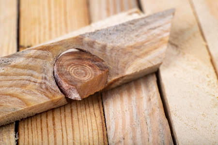 A hard knot in a raw slat. A knot from a piece of wood. Light background.