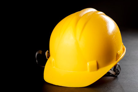 Yellow work helmet on a dark table. Protective accessories for construction workers. Dark background.の写真素材