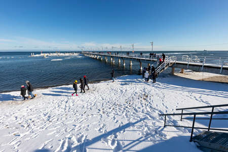 Mechelinki, Pomorskie Poland - February, 14, 2021: Pier and walking tourists. A place of rest in a small fishing village. Winter season.のeditorial素材