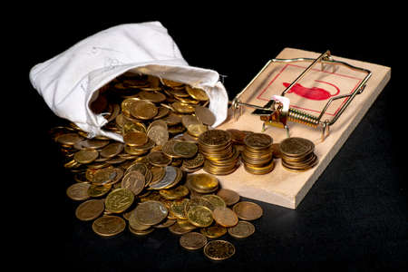 Mouse trap and coins. A trap in the form of money. Dark background.