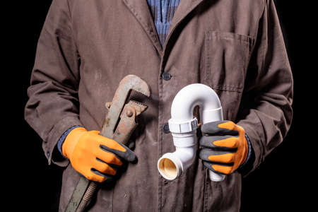 Plumber holding an adjustable wrench and a siphon to the wash basin. Worker repairing the hydraulic...