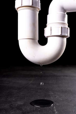 Water leaking from the drain pipe. Household drainage failure. Dark background.の写真素材