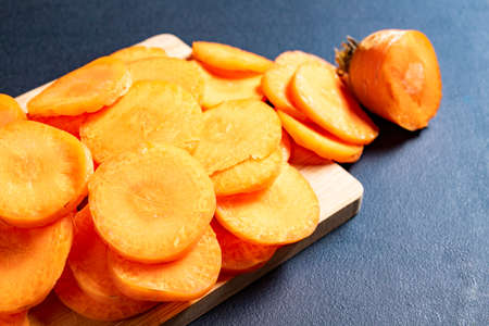 Tasty carrot slices arranged on a wooden board. Vegetables prepared for serving in home cooking. Dark background.の写真素材
