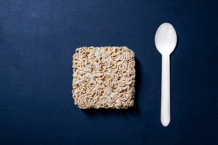Chinese noodle soup on the kitchen table. Disposable wooden cutlery for eating instant meals. Dark background.の写真素材