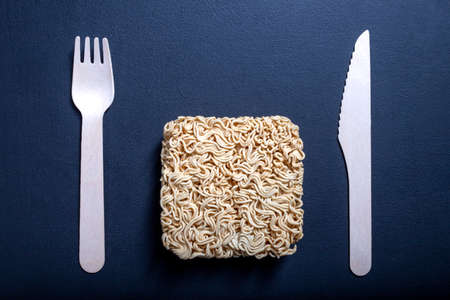 Chinese noodle soup on the kitchen table. Disposable wooden cutlery for eating instant meals. Dark background.の写真素材