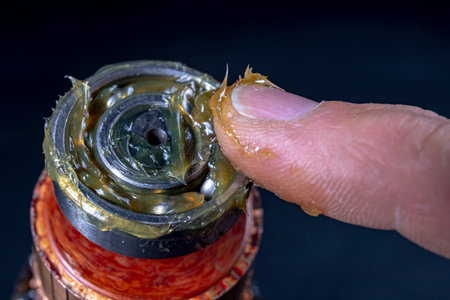 Ball bearing lubrication with grease. Assembly work in a mechanical workshop. Dark background.の写真素材