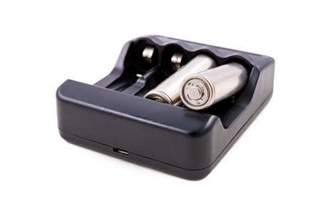 Black charger and silver batteries for energy storage. Accessories for powering household appliances. Light background.の写真素材