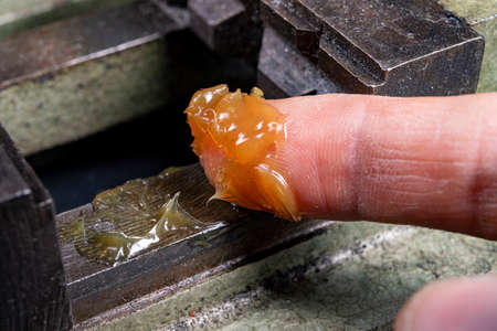 Lubrication of elements of a mechanical vice. Coating metal parts with a layer of mechanical grease. Dark background.の写真素材